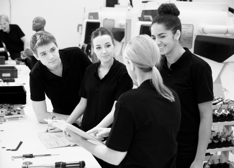 Engineer in factory with apprentices checking components